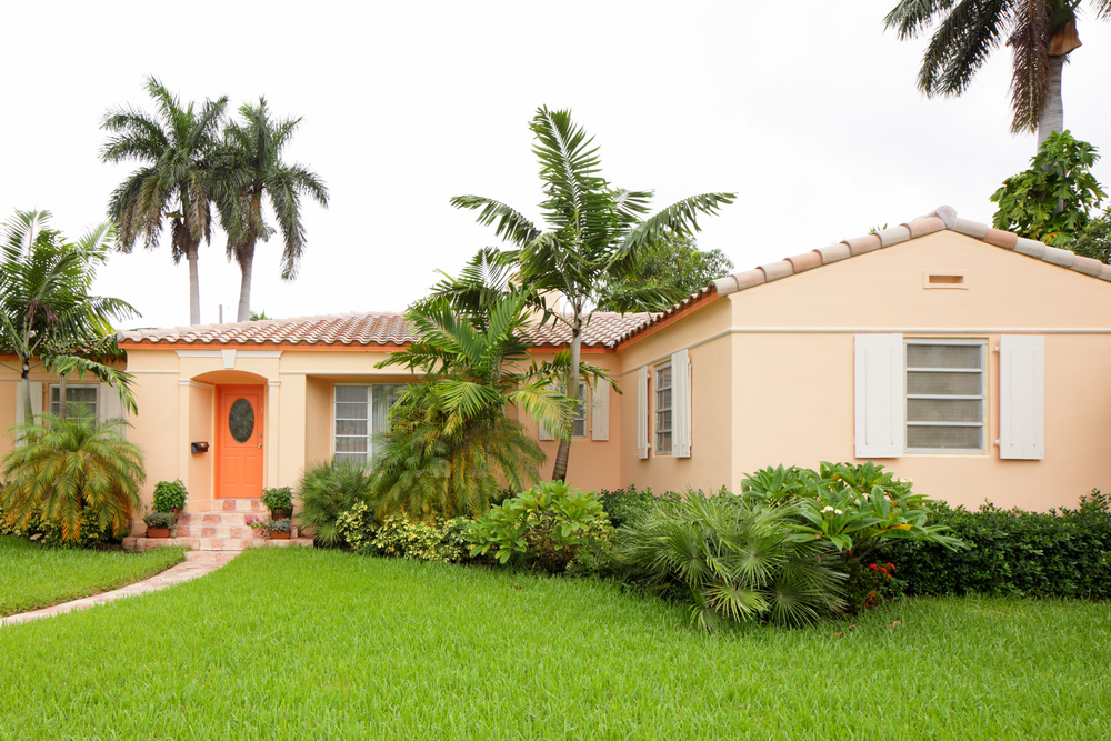 A South Florida home with art deco design, lush lawn, and healthy palm trees