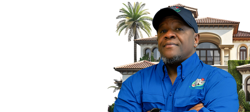 A person in a blue shirt and cap stands confidently with arms crossed. They are in front of a large, elegant house with a palm tree, against a white background.