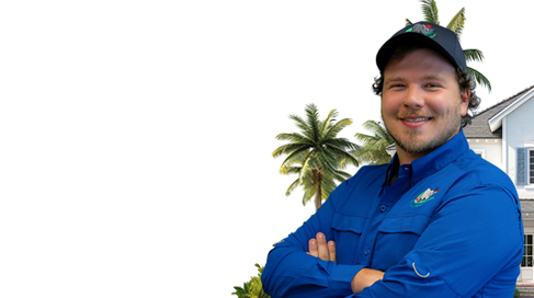 A person in a blue shirt and black cap smiles with arms crossed. A palm tree and a house are in the background. The left side of the image has a white space.