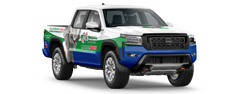 A white and blue pickup truck with green accents and various logos on its sides. The truck features a modern design with a prominent front grille and large wheels.